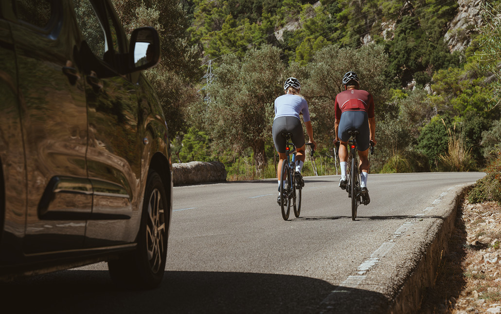 Two road cyclists with SIGMA RECO 81 LINK rear lights are riding on a winding country road.